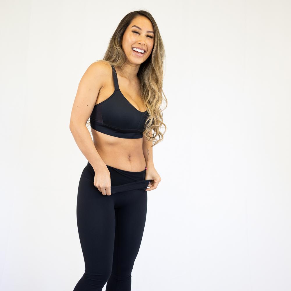 Woman in black workout attire happily modeling Emamaco shapewear leggings with pockets