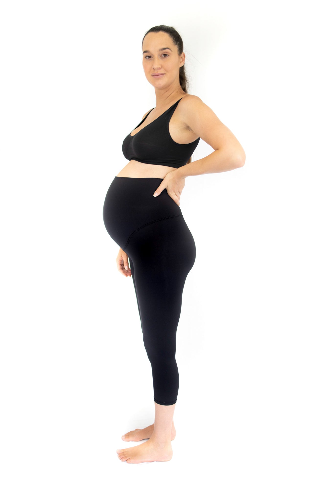 Pregnant woman in side profile showcasing completely specialised maternity leggings in black