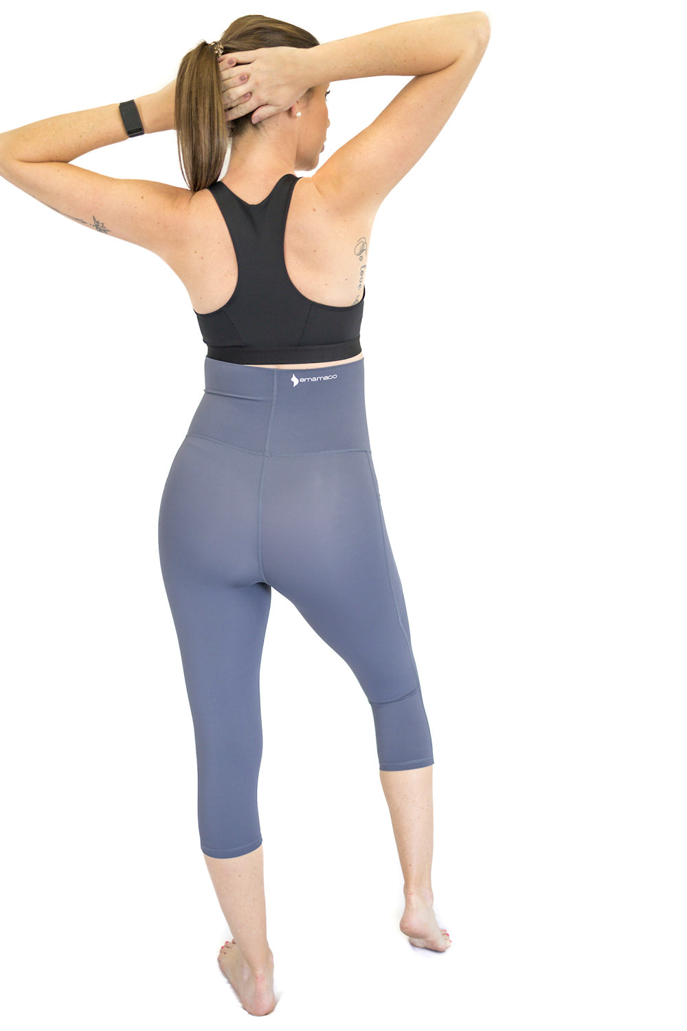 Woman in blue 3/4 Maternity Leggings with pockets and black sports bra, hands behind head