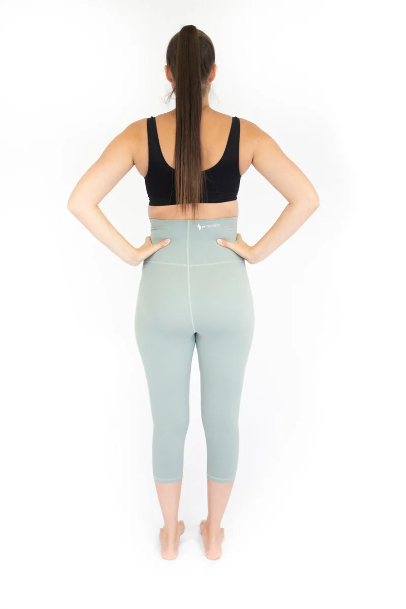 Woman in black sports bra and blue high-waisted maternity leggings, showcasing comfort