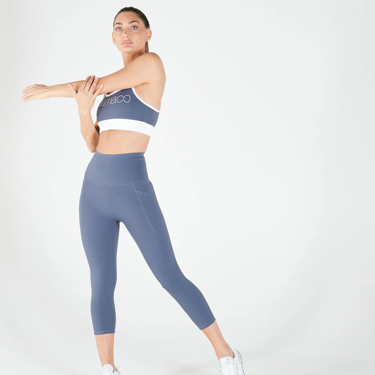 Woman in blue activewear stretching in 3/4 Shaper Move Leggings - TWILIGHT