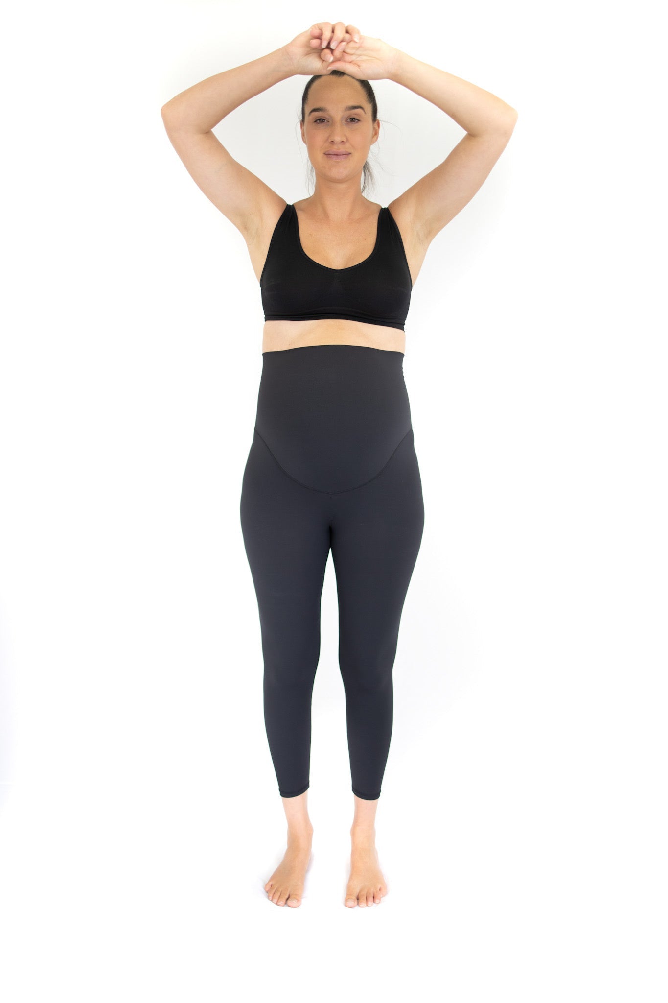 Woman in athletic wear with arms raised showcasing Emamaco Maternity Leggings in Black