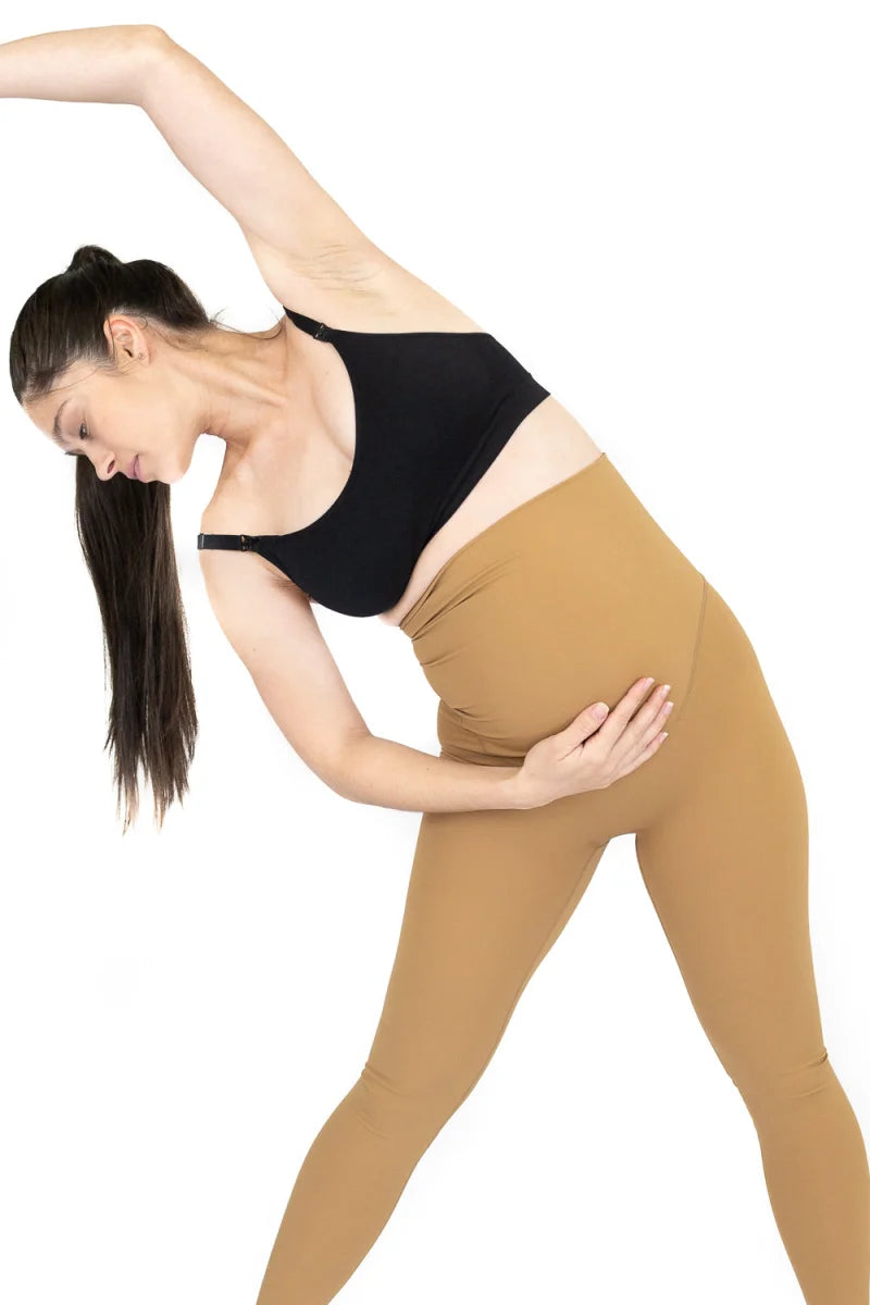 Woman in athletic wear demonstrating a side bend stretch in 7/8 Maternity Leggings FINAL SALE