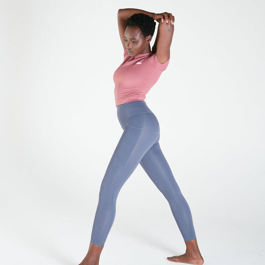 Woman in pink top and blue leggings stretching in Shaper Move Leggings maternity activewear