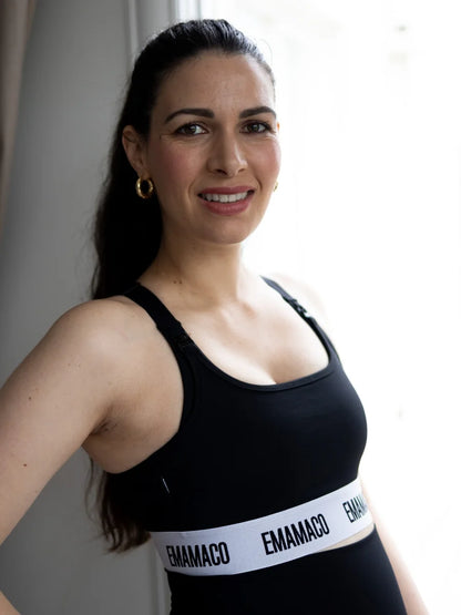 Woman with long dark hair smiling in the Aware Nursing Sports Bra - Black