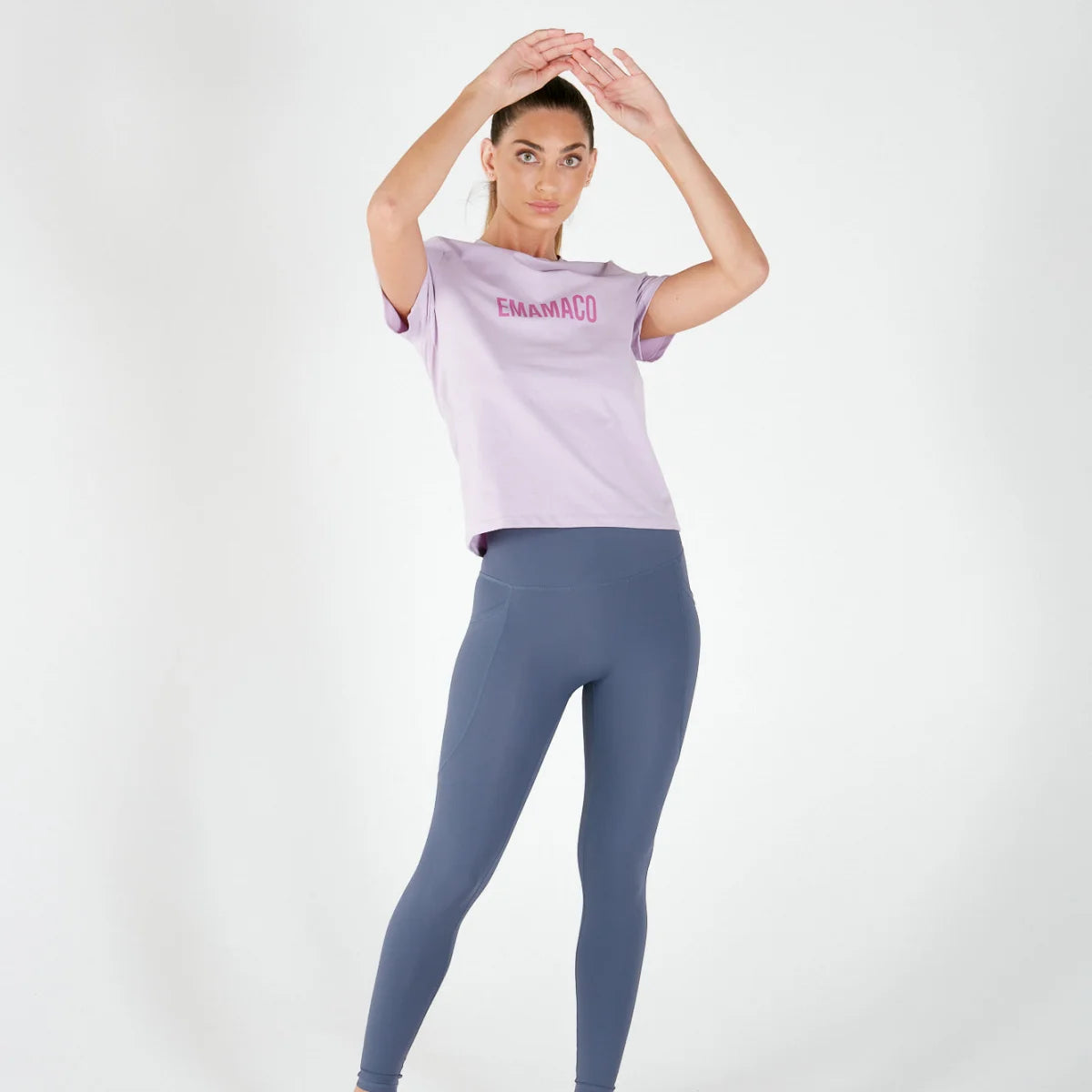 Woman in light purple BASIC TEE and blue leggings celebrating final sale of maternity activewear