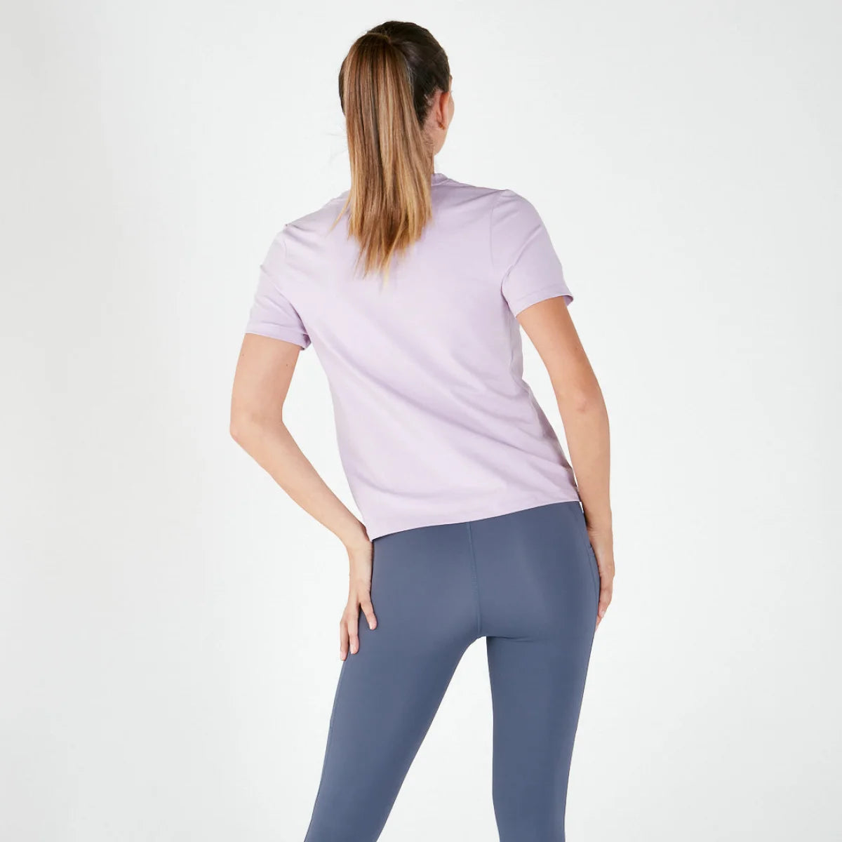 Woman in light purple t-shirt and blue leggings showcasing maternity activewear final sale