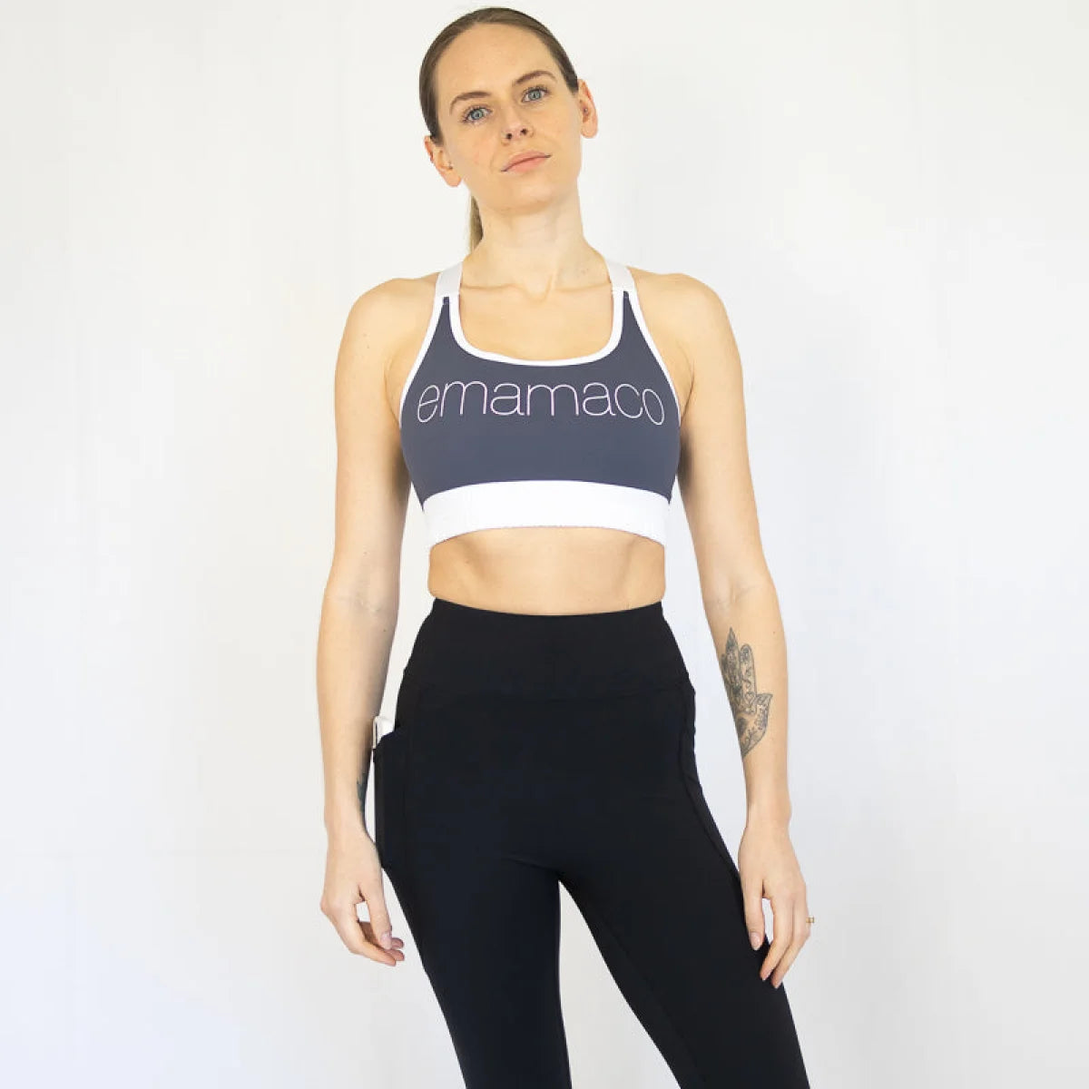 Woman in navy blue Elevate Nursing Sports Bra with emamaco text and black leggings