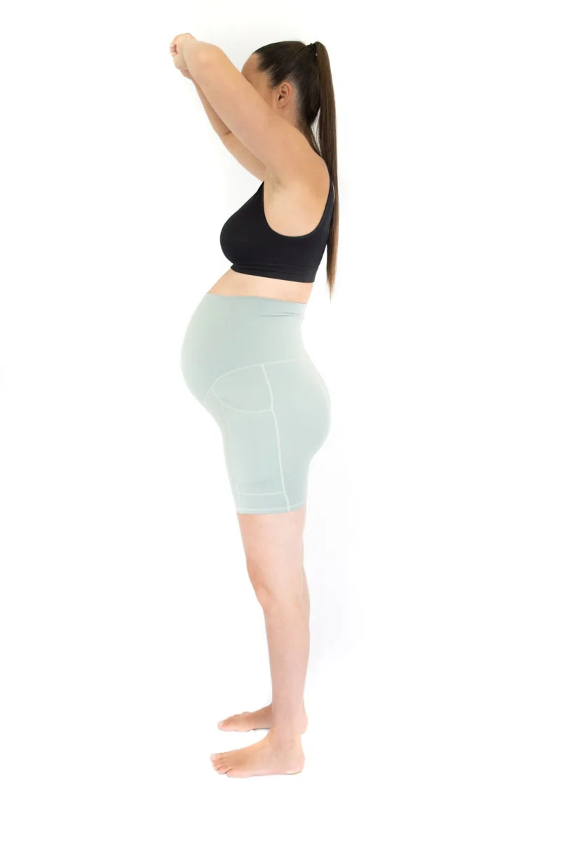 Woman wearing Emama Maternity Bike Shorts with pockets and mint green fitted skirt