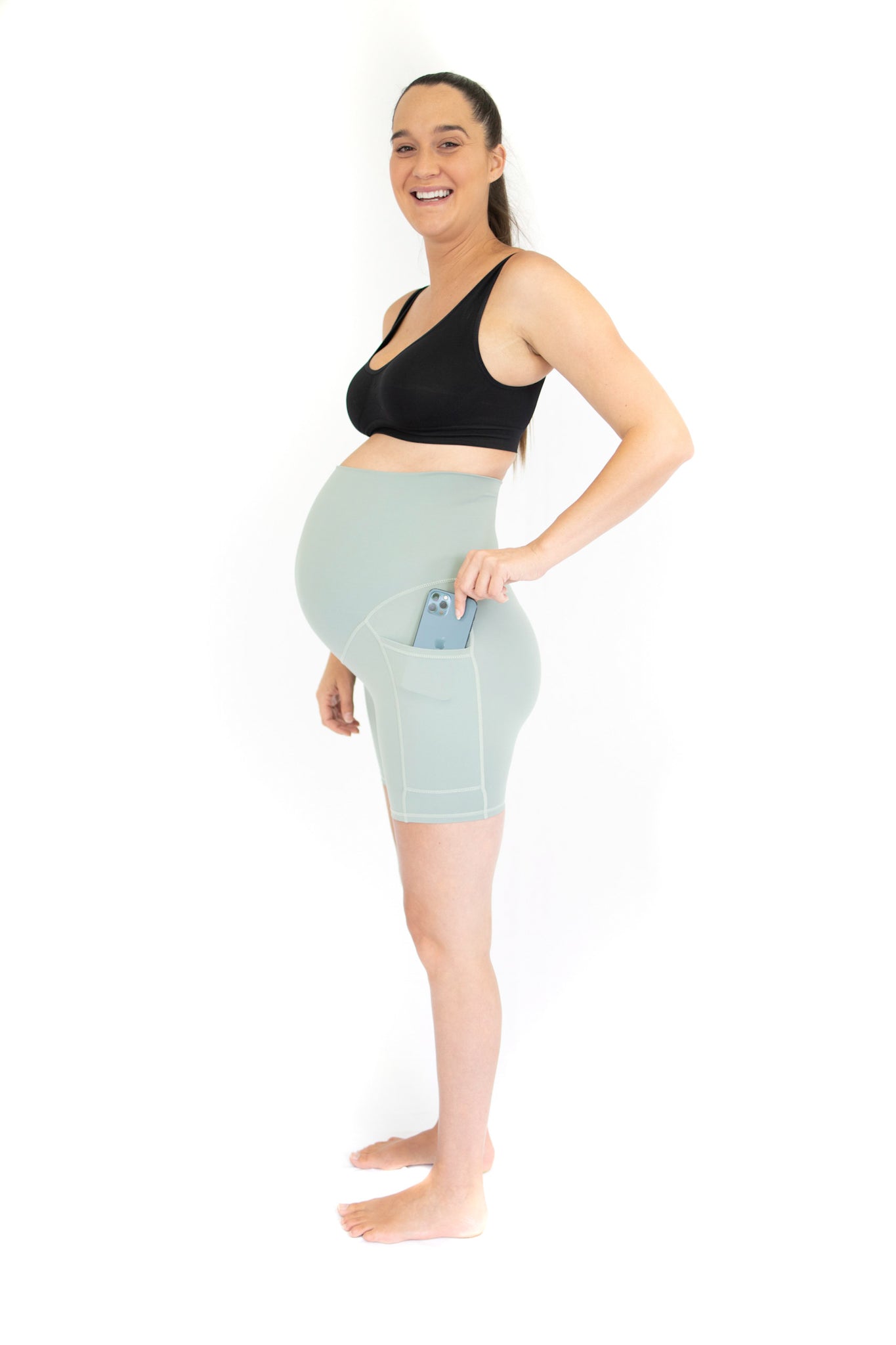 Pregnant woman in EmamaCo Maternity Bike Shorts with pockets and a black sports bra