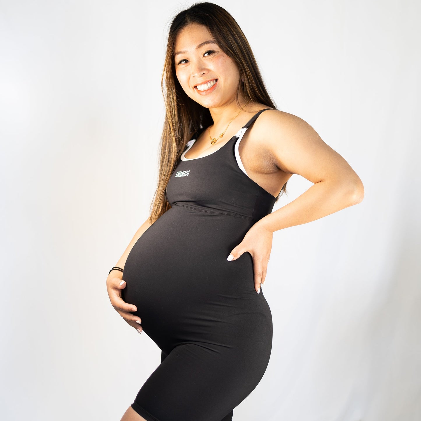 Pregnant woman in black athletic outfit wearing Emama Nursing Maternity Bodysuit