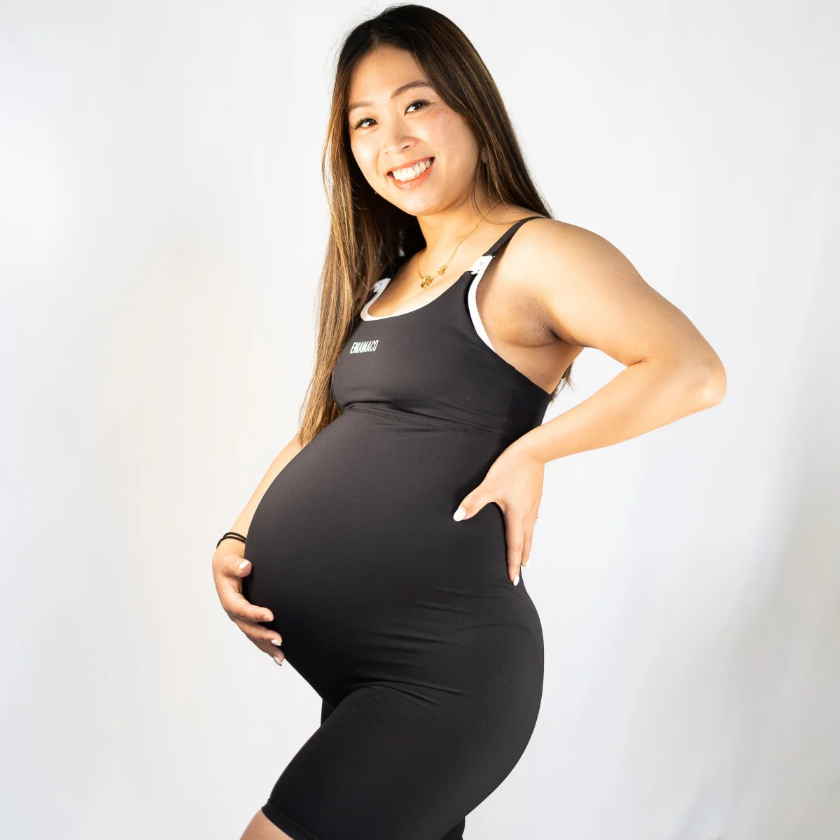 Pregnant woman in black athletic outfit wearing Emama Nursing Maternity Bodysuit