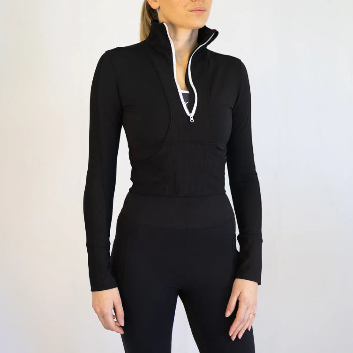 Black long-sleeved Rosetta Top with white-trimmed quarter-zip for body hugging sports