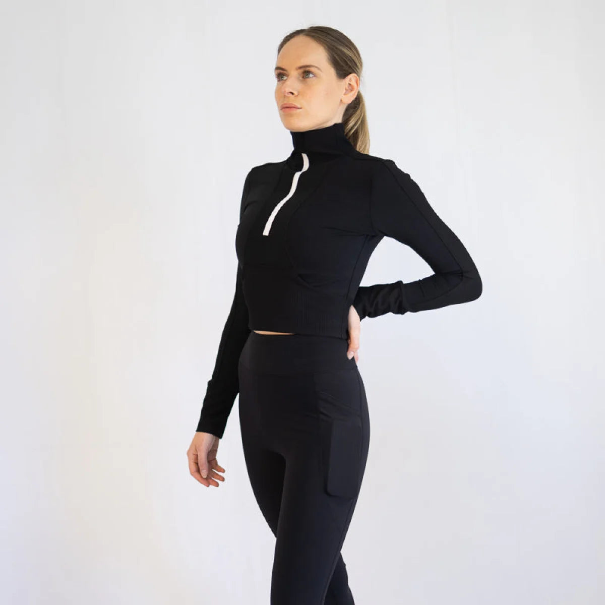 Woman in Rosetta Top in Black, a body hugging athletic outfit with long sleeves