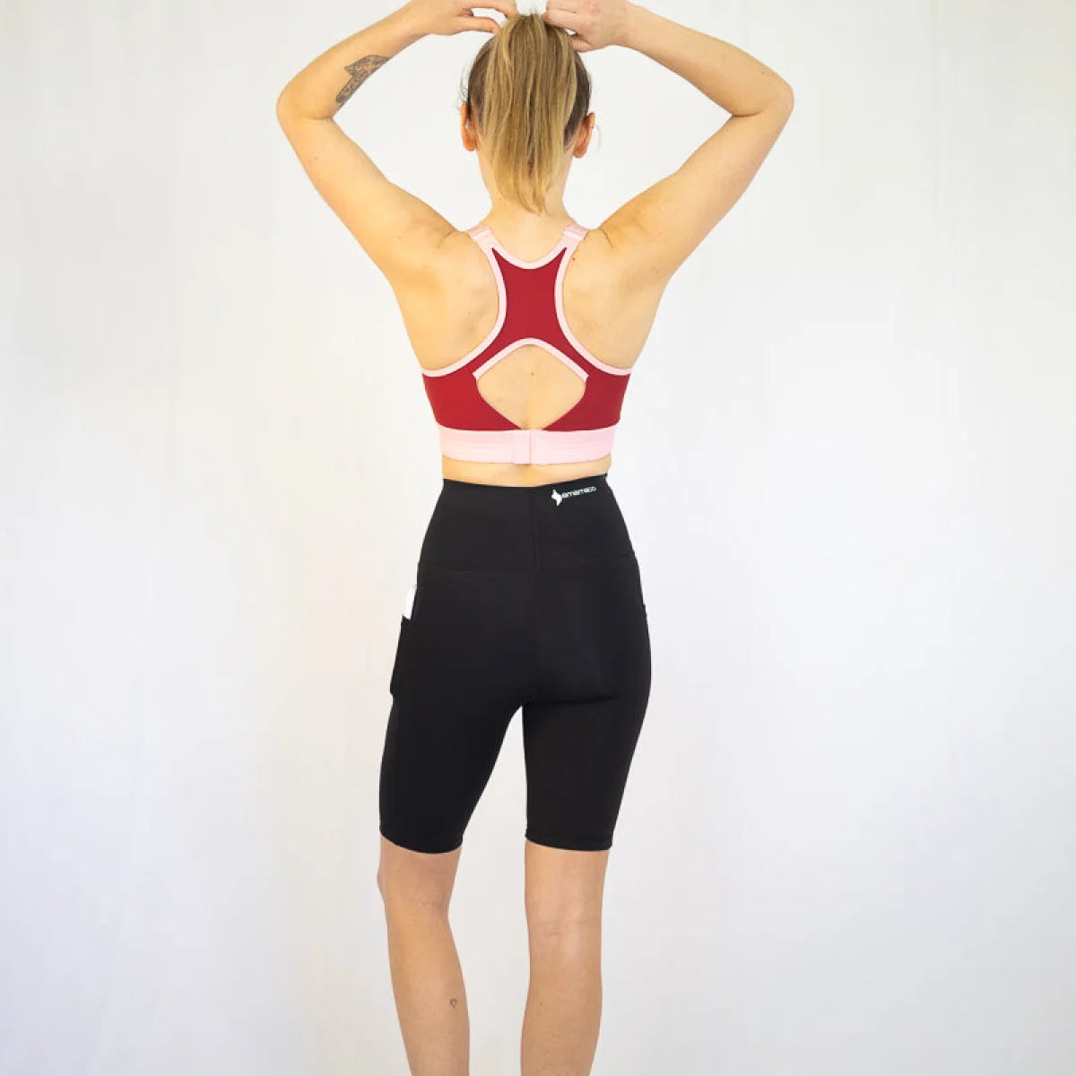 Woman in red sports bra and black long shorts, perfect for pet hair and maternity wear