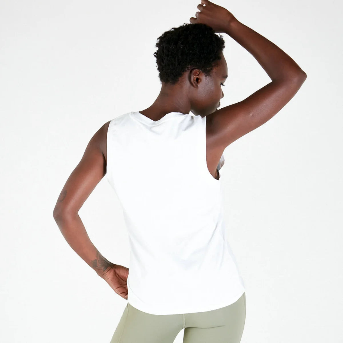 Person in white sleeveless tank top raised arm, a stylish addition for maternity activewear