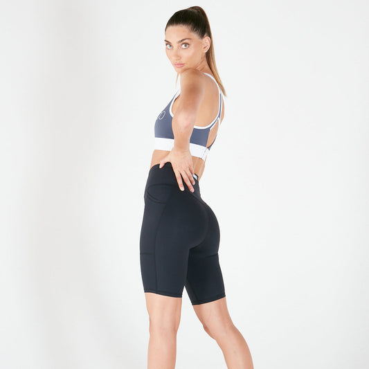 Woman in navy blue v-back long shorts and matching sports bra with white trim